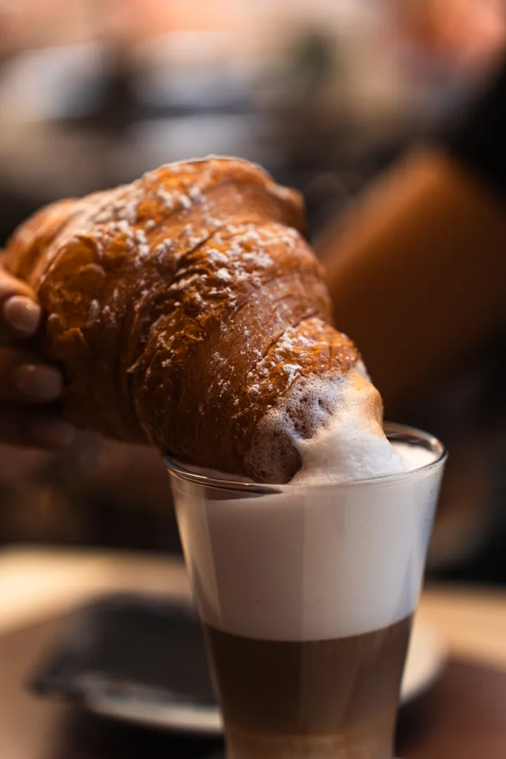 Una brioche intinta nel latte macchiato per la colazione al Mastino Bistrot, in Piazza delle Erbe a Verona