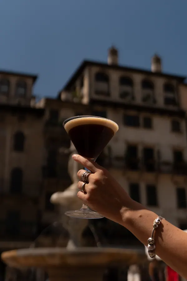 Un espresso martini sollevato davanti ai palazzi di Piazza delle Erbe – Il Mastino Bistrot, Verona